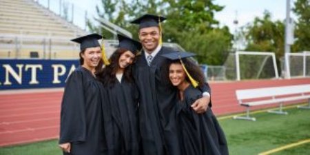 Students hugging in graduation cap and gowns.